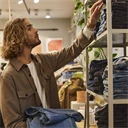 Man sorterar byxor i en butik.