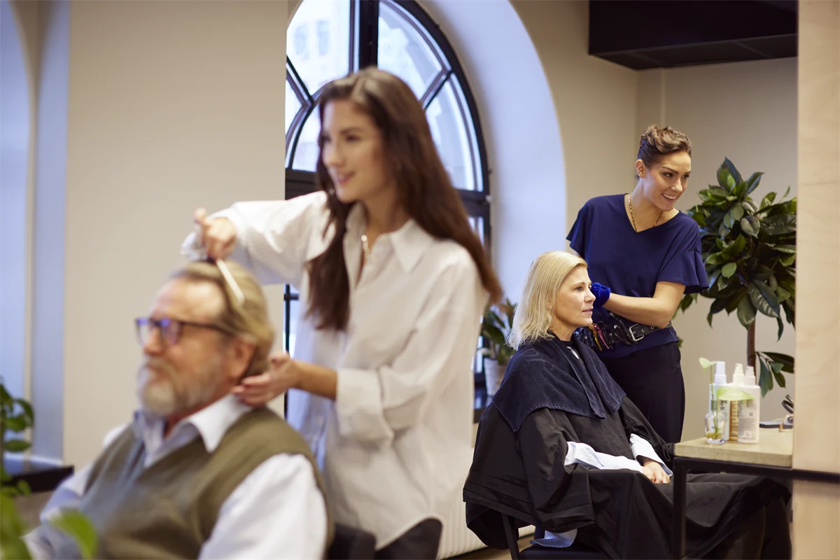 Kvinnliga frisörer med kunder i salong.