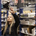 Ung kvinna som jobbar på lager, registrerar varor på en skärm.