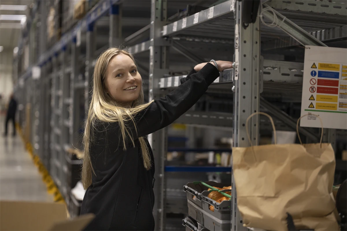 Ung glad kvinna som jobbar på lager.