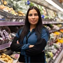 Ung kvinna som jobbar i butik, står med armarna i kors och har ett bestämt uttryck.