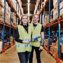 En ung kvinna och ung man som arbetar på lager, iklädda reflexväst.